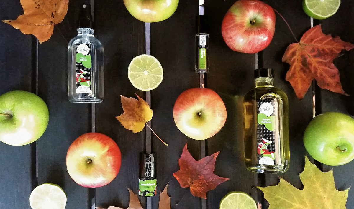 MBeze Once BItten Collection surrounded by apples, limes, and fall leaves. Including the Body Mist, Deodorette, Perfume, and Body OIl.